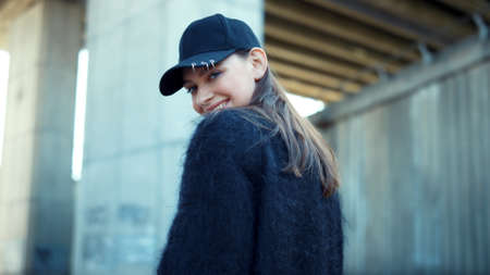 Portrait of happy girl posing at camera. Stylish hipster laughing outdoors. Girl positive emotion. Closeup fashion model flirting with camera. Smiling woman portrait on city street.の写真素材