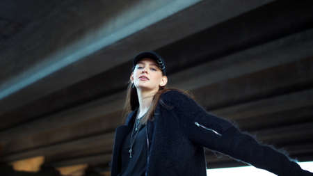 Positive girl turning around on urban street. Smiling woman raising hands. Fashion lady looking at camera. Attractive hipster woman posing outdoors. Female model girl wearing casual capの写真素材