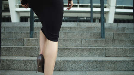 Portrait elegant woman legs going upstairs in stylish shoes outdoors. Successful woman entrepreneur looking away at street. Sexy business woman walking in high heel shoes in slow motion outside.の写真素材