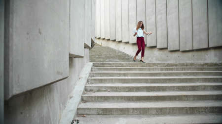 Focused business woman working with documents in city. Busy female manager walking down stairs on urban street. Attentive businesswoman examining financial statistics outdoors. Woman going for workの写真素材