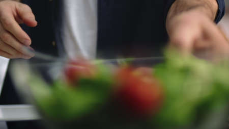 Closeup man hands taking bowl with salad at home kitchen. Unrecognizable male person starting eat...
