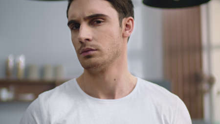 Portrait of serious man looking camera at home kitchen. Closeup focused man crossing hands indoors. Handsome sexy guy standing on kitchen background.の写真素材