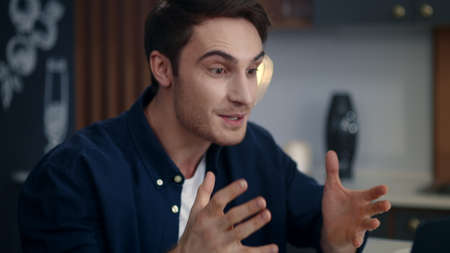 Portrait of excited businessman celebrating success on video call at remote workplace. Happy guy...