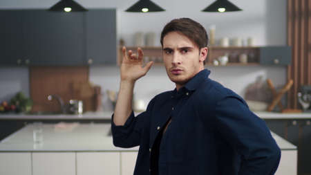 Portrait of sporty man posing to camera on modern kitchen. Attractive guy dancing at home kitchen in...