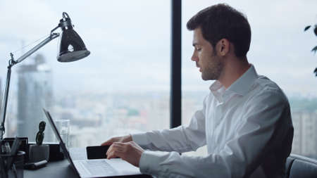 Successful businessman working on laptop computer at remote workplace. Serious professional looking...