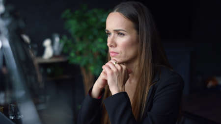 Focused businesswoman thinking about work in office. Thoughtful woman holding hands at face. Serious...