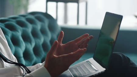 Unrecognizable businessman having video chat on laptop with green screen. Male hands gesturing at camera during video chat. Closeup unknown business man clapping hands at home officeの写真素材