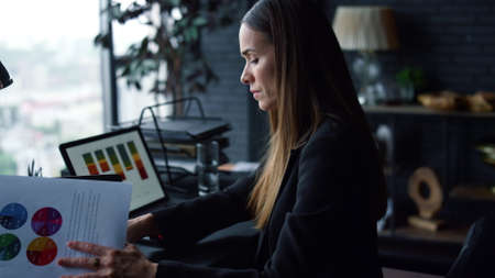 Portrait of focused businesswoman working with papers in office. Female professional looking at...