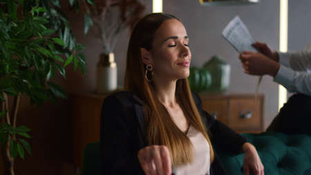 Smiling businesswoman sitting on couch with businessman in modern office. Displeased business man...