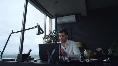 Positive businessman talking with business partner during video chat in office. Corporate employee...