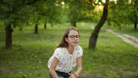 Close up smiling teen girl dancing outside. Happy teenage girl making rhythmical movements in summer park. Cheerful girl moving funny otdoors in slow motion.の写真素材