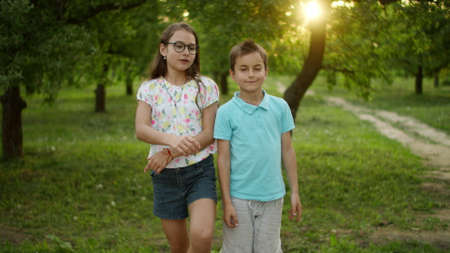 Smiling brother and sister dancing outside. Cheerful boy throwing frisbee plate outdoor in slow...