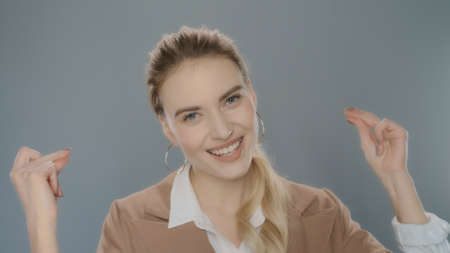Happy business woman snapping finger on grey background. Portrait of smiling girl snap fingers....