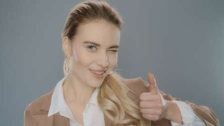 Portrait of successful business woman showing thumb up. Confident professional showing thumbs up in...