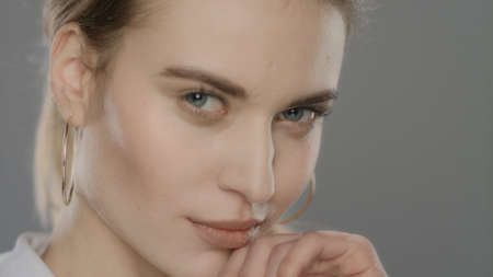 Sexy woman face. Portrait of young woman touching face with hand in slow motion. Close up of sensual...
