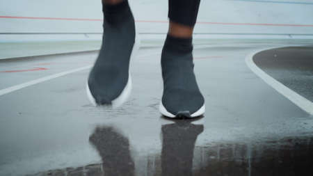 Jogger in sports shoes running on spot in slow motion. Active man legs running on racetrack. Sporty...