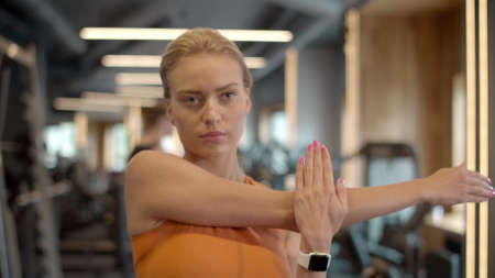 Progressive athlete girl making exercises in fitness center. Closeup sportswoman preparing to workout in sport club. Attractive serious fitness woman warming up hands at gym.の写真素材