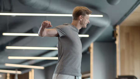 Serious fitness man warming up shoulders in sport club. Attractive bodybuilder preparing to crossfit...