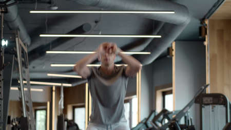 Focused bodybuilder making squats in sport club. Closeup strong sportsman jumping in fitness center....