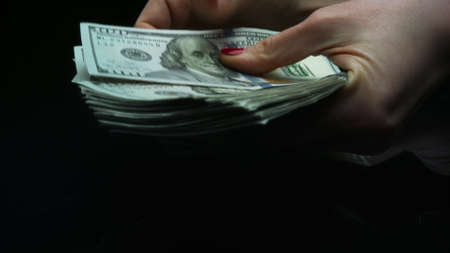 Macro shot female hands holding money cash, finance and cash concept. Closeup successful businesswoman hands counting one hundred dollar banknotes. Unrecognizable woman counting dollar billsの写真素材