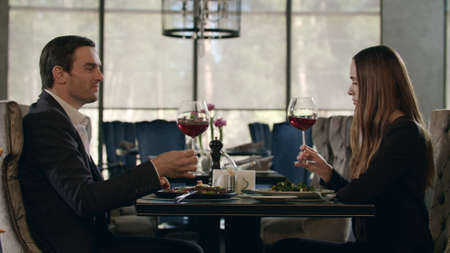 Man and woman tasting red wine from glass at restaurant dinner. Romantic couple enjoying red wine at lunch in cafe. Business couple dining in restaurantの写真素材
