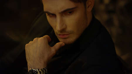 Portrait of serious man thinking about business in dark office interior. Closeup elegant man face...