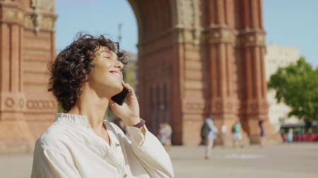 Portrait of smiling man talking mobile phone outdoor in slow motion. Close up cheerful guy making...