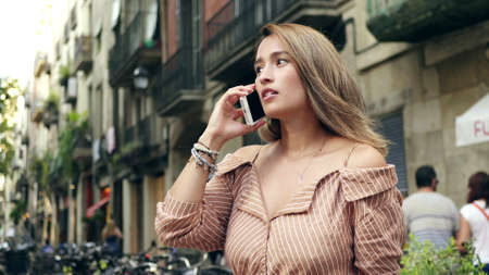 Portrait of smiling woman talking mobile phone at urban street in slow motion. Close up pretty girl making call on city background. Focused woman discussing by cellphone outdoor.の写真素材