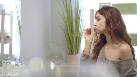Smiling woman brushing teeth with toothbrush and toothpaste front mirror in bathroom. Young girl cleaning teeth in bath room. Dental hygiene and careの写真素材