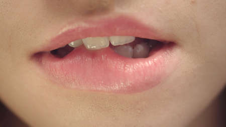 Sensual woman biting and licking plump lips. Close up young woman face biting  lips and licking with...