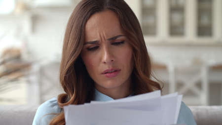 Closeup sad business woman reading documents at home office. Portrait of disappointed girl working...