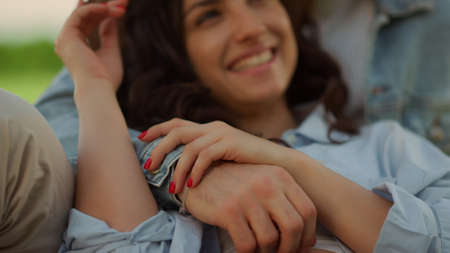 Portrait of cute couple spending time on picnic in summer park. Closeup attractive man touching woman hair on romantic date outdoors. Charming girl laughing while lying on guy in park.の写真素材