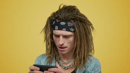 Portrait of focused man playing game on smartphone in studio.