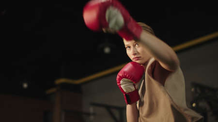 Closeup serious sport woman doing punches at gym. Portrait active of female boxer warming up in sport club. Attractive fit girl boxing in fitness center.の写真素材