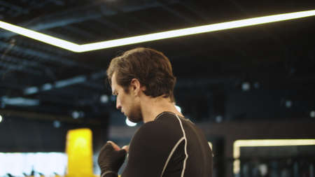 Closeup focused fitness man warming up before fight in sport club. Eager male boxer using skipping...