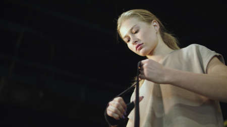 Closeup serious female athlete wrapping hands with boxing bandage in sport club. Focused fit girl...