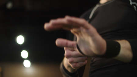 Closeup unrecognizable man wrapping hands with boxing bandage in fitness center. Unknown man...