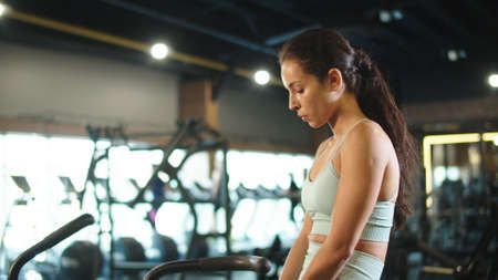 Side view of exhausted fit girl sitting in sport club. Closeup tired sport woman making break at...