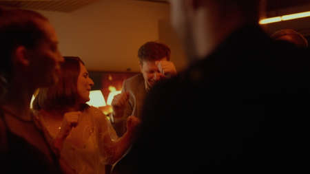 Multiracial group of people dancing on party. Cheerful friends celebrating birthday in bar. Playful...