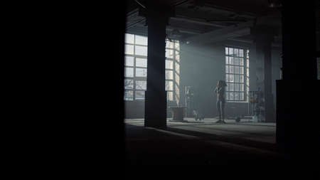 Exhausted sportswoman walking dark gym at fitness training. Female athlete stretching neck muscles....