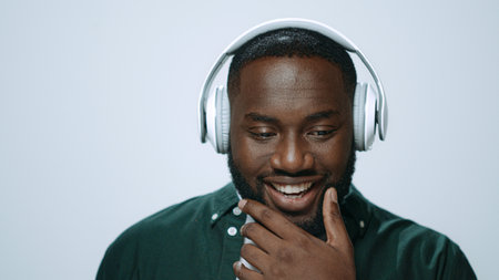 Portrait positive man listening music on earphones indoors. Closeup african american dj enjoying...