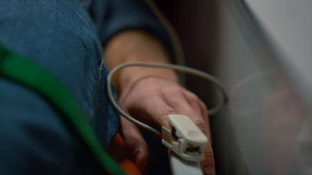 Unrecognizable medical worker putting pulse oximeter on patient finger. Female paramedic checking man oxygen blood level. Closeup male victim in oxygen mask lying on stretchers in emergency carの写真素材