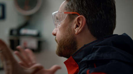 Emotional paramedic having conversation with colleague in emergency car. Closeup angry male doctor in protective glasses gesturing hands. Portrait of emergency care assistant waving head noの写真素材