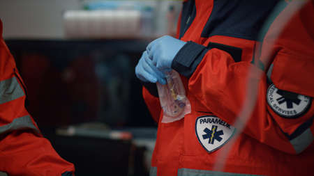 Medical team rescuing patient after car accident in emergency vehicle. Professional paramedic checking patient stomach with stethoscope. Emergency doctors giving first aid to victim with oxygen maskの写真素材