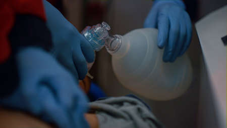 Unrecognizable paramedics hands providing cardiac massage on chest of patient. Medical workers using...