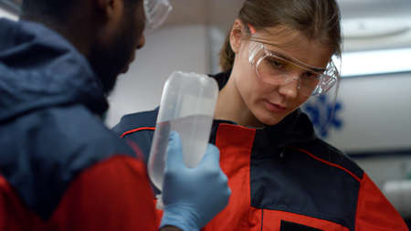 Mixed race health care professionals preparing for medical help procedure. Afro doctor and medical assistant working together in emergency vehicle. Tired paramedics talking after hard work at nightの写真素材