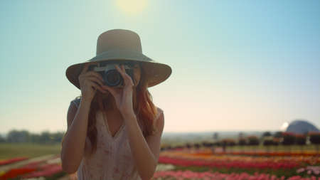 Professional woman photographer making photo in beautiful spring garden with many flowers. Pretty...
