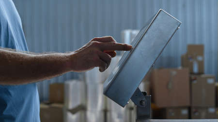Closeup unknown factory worker weighting goods calculating production supply typing. Close up...