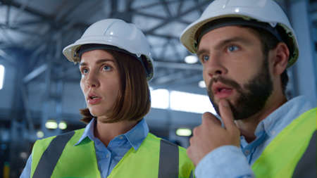 Portrait factory supervisors discussing supply production shipment process. Two green reflective uniformed warehouse employees talking about distribution checking tablet. Job partnership conceptの写真素材