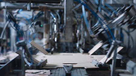 Automated factory cardboard production at mechanical modern manufacture closeup. Technological storehouse technology of cardbox distribution automation. Warehouse tech product machinery conceptの写真素材
